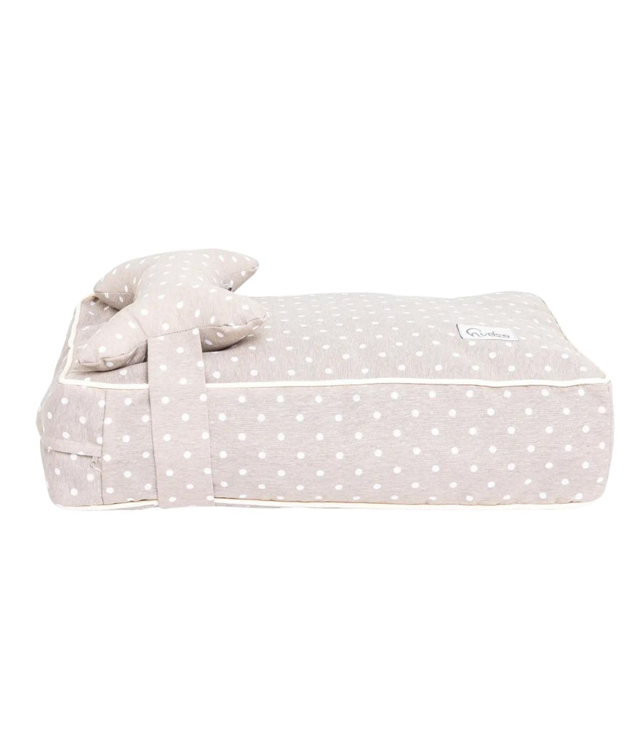 Cuccia letto per cani beige con pois bianchi e cuscino a forma di osso, vista laterale con sfondo bianco.