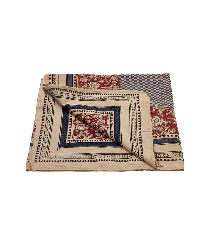 Tovaglia rettangolare in cotone con pattern fine a quadretti neri e bianchi, circondato da una larga bordura rossa e beige decorata con motivi floreali intricati. Vista piegata. 