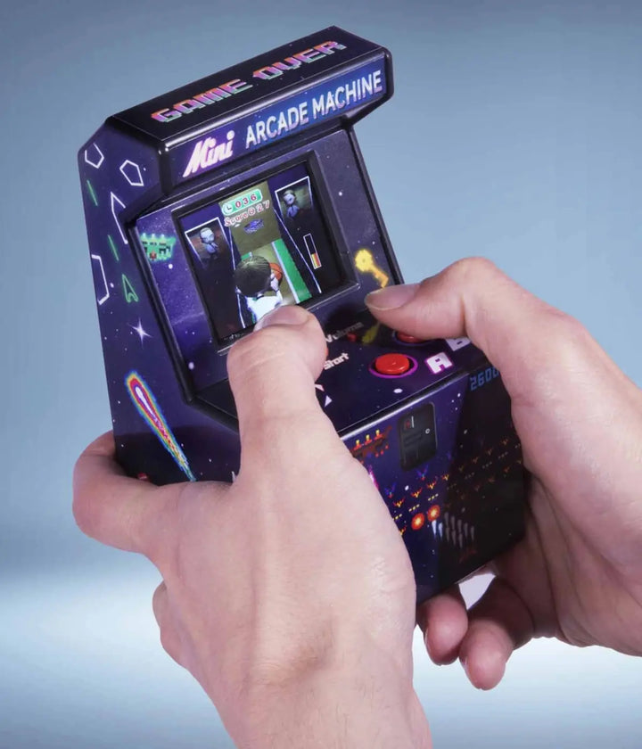 Due mani che giocano con l'Arcade portatile. Scritta Game over e Mini Arcade Machine. Sfondo azzurro